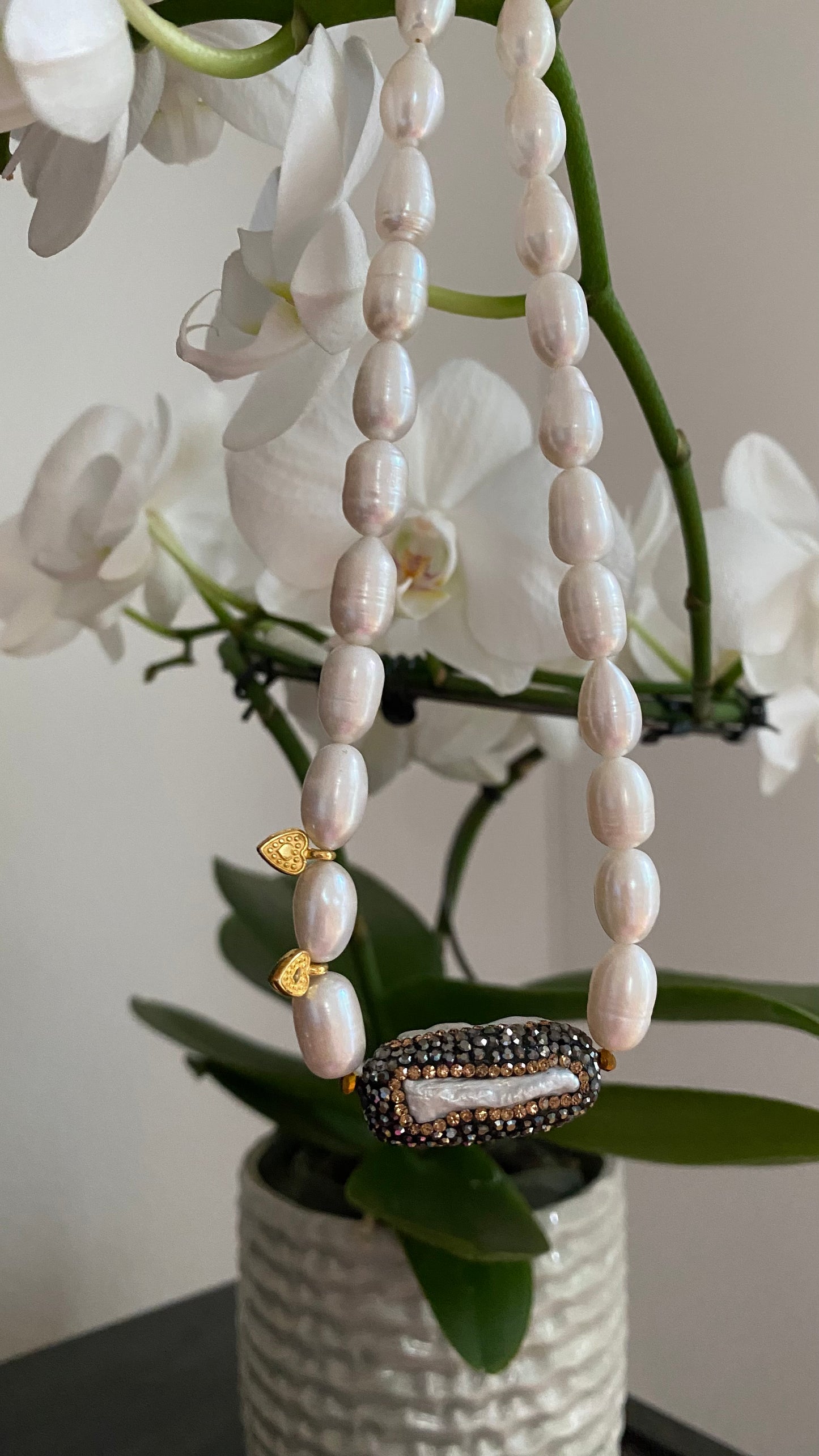 Elegante handgefertigte Halskette aus weißen Süßwasserperlen mit funkelndem Kristallanhänger und vergoldetem Verschluss.