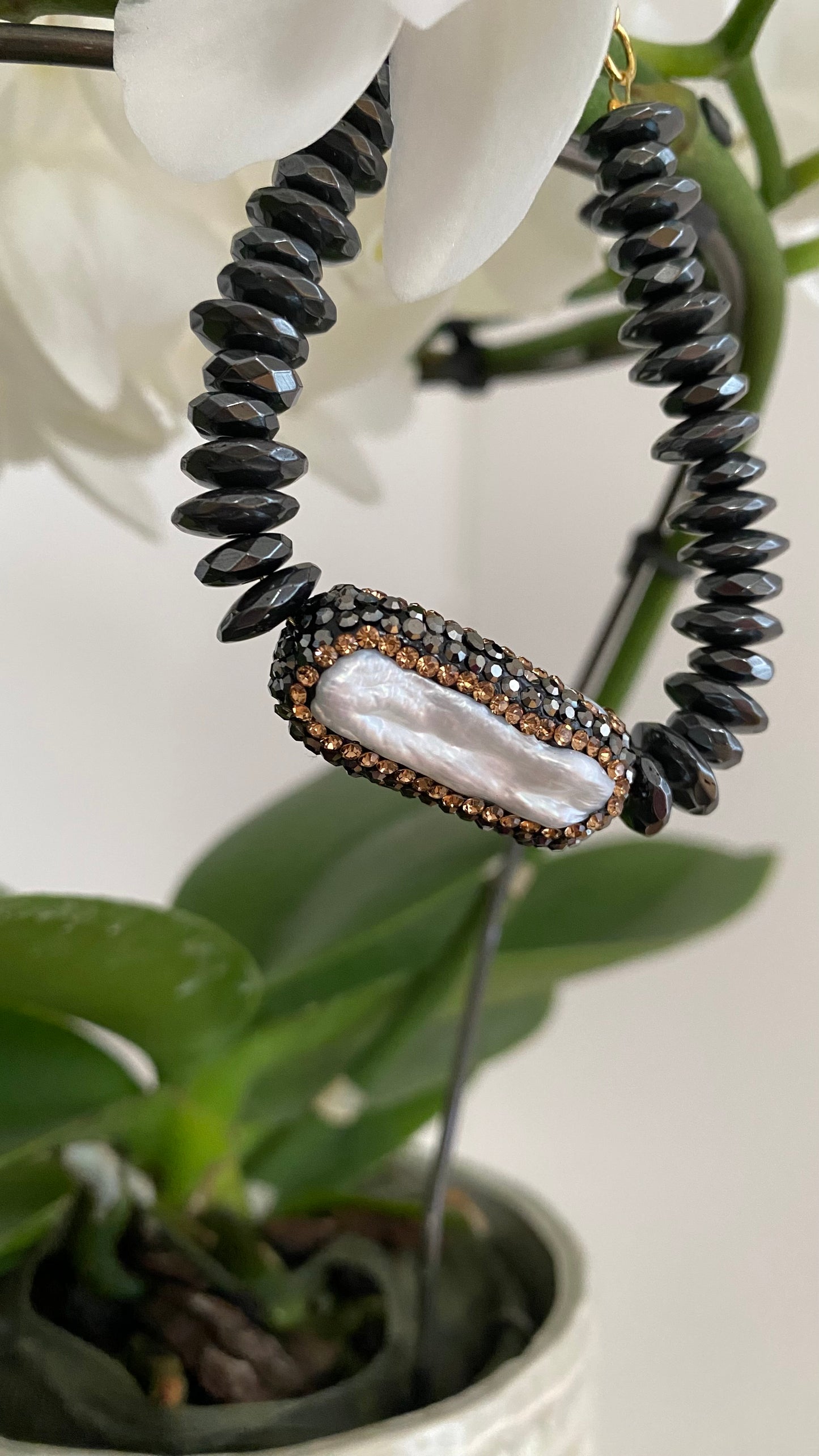 Edles schwarzes Perlenarmband mit glänzenden Kristallen und goldfarbenem Verschluss.